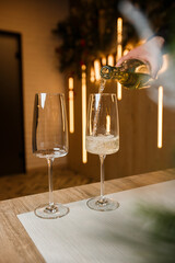 Dispensing golden white wine into two wineglasses in a close up on the neck of the bottle over wood with copy space in a tilted angle view