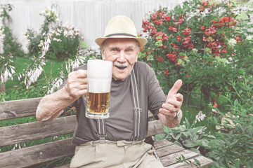 gray-haired old man in a hat with a glass of fresh beer. Outdoor recreation after work.