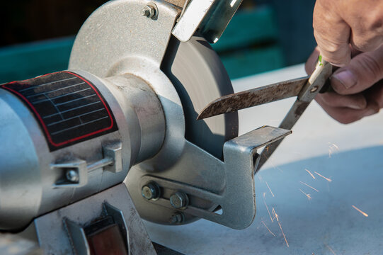 Manual sharpening of scissors using hand tools. Circumcised Hands Of An Unknown Person Sharpening Scissors On A Typewriter. man sharpens scissors