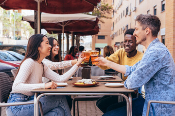 multiethnic group of 4 friends toasting on a restaurant terrace