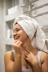 Closeup portrait laughing woman with towel on hairs posing peeling scrub mask on face at bathroom