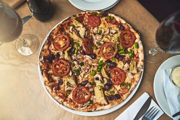 Have a slice. High angle shot of a full plate of pizza resting on top of a table inside of a restaurant during the day.