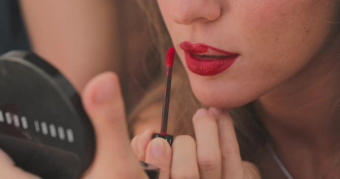 Close up slow-motion footage of how a girl with a burgundy pencil for makeup outlines the contour of the lips, preparation for the performance