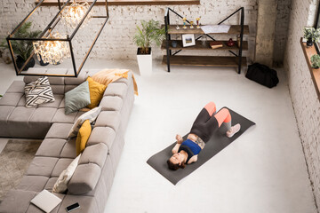 Caucasian woman laying at home at the yoga mat, while doing her morning exercises