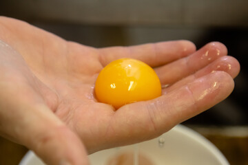 Egg yolk separate on the hand for cooking,food ingredient - obrazy, fototapety, plakaty