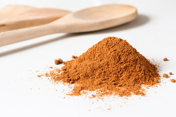 Nutmeg on white surface with wooden spoons