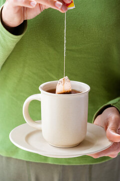 Woman Holding Cup Of Tea And Tea Bag. Close Up