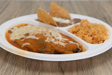 Chile relleno covered in cheese and served with rice and beans to eat for lunch