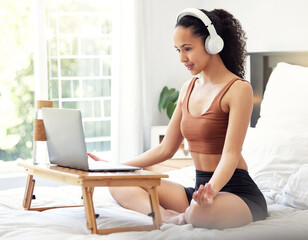 Time for my daily dose of zen. Shot of a young woman meditating while using a laptop at home.