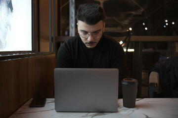 man working with laptop in cafe