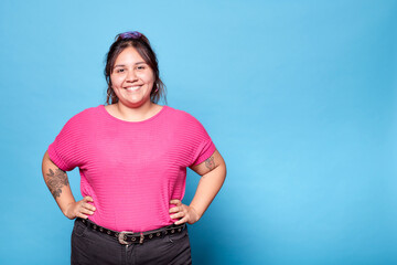 Young curvy latina woman smiling looking at camera isolated on blue background. Copy space. - obrazy, fototapety, plakaty