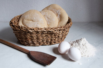 Syrian bread inside a basket with eggs and flour around