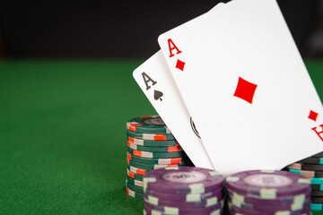 A pair of aces sit amongst several stacks of poker chips. 
