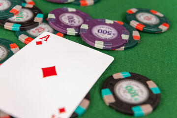 A playing card sits on casino chips on a poker table. 