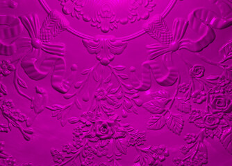 Inside of a moulded plastic light fitting with a pink hue. Ornate raised flowers and bows made out of the plastic