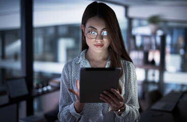 Working into the night to make success hers. Shot of a young businesswoman using a digital tablet in an office at night.