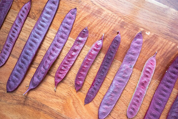 Purple Guaje seed pods are arranged in a pattern on a table.