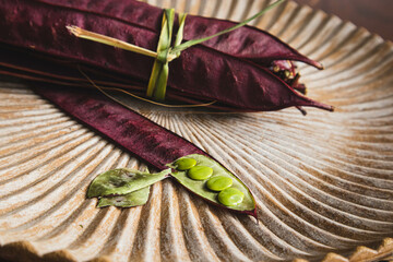 Obraz premium Bundle of purple Guaje bean pods on a plate next to an open bean pod with exposed seeds. Oaxaca, Mexico.