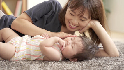 Obraz na płótnie Canvas 床に寝そべる赤ちゃんとお母さん