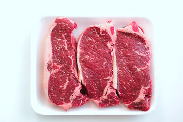 Fresh raw beef steak in foam plate from supermarket isolated on white background.  Meat prices rise and global food crisis due to inflation concept. Ready to cook. Tender and juicy meat texture.