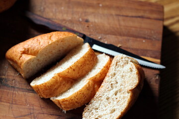 wheat bolillos made from wheat being sliced and ready to serve On a wooden cutting board at the kitchen table. Flat-lat photo.