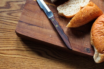 wheat bolillos made from wheat being sliced and ready to serve On a wooden cutting board at the kitchen table. Flat-lat photo.