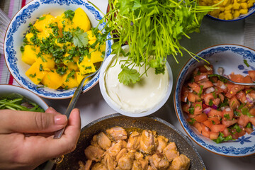 Sour cream, salsa, mango, cilantro, and fried salmon in bowls on a table, ingredients for fish tacos.