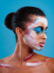 Always put your best side forward. Studio shot of a beautiful young woman covered in face paint posing against a blue background.