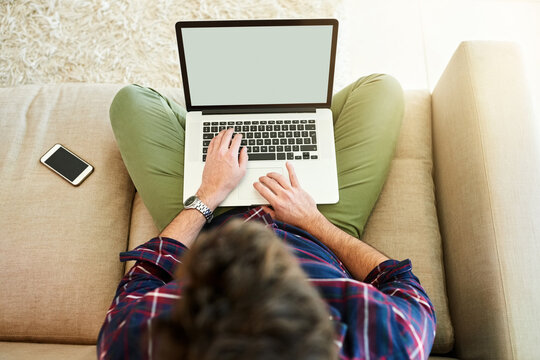 Get comfortable, get connected. High angle shot of a young man using a laptop on the sofa at home.