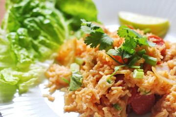 Vertical picture, pork and sausage fried rice served in a plate with lettuce and coriander garnish. Fried rice is a street food that is sold in Thailand.