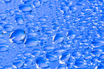 Water drops on a blue glass surface exrtreme close-up view