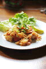 Vertical picture, pork and sausage fried rice served in a plate with lettuce and coriander garnish. Fried rice is a street food that is sold in Thailand.