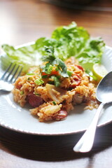 Vertical picture, pork and sausage fried rice served in a plate with lettuce and coriander garnish. Fried rice is a street food that is sold in Thailand.