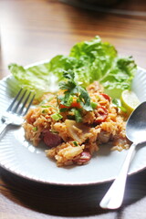 Vertical picture, pork and sausage fried rice served in a plate with lettuce and coriander garnish. Fried rice is a street food that is sold in Thailand.