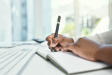Write down your daily goals before you start each day. Cropped shot of an unrecognizable businesswoman writing in her notebook while sitting at her desk.