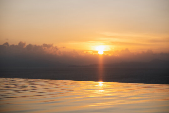 Landscape image of a beautiful sunset sky over the infinity swimming pool and the sea view