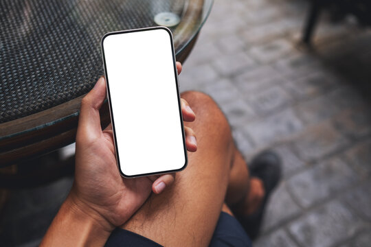 Top view mockup image of a man holding mobile phone with blank white screen