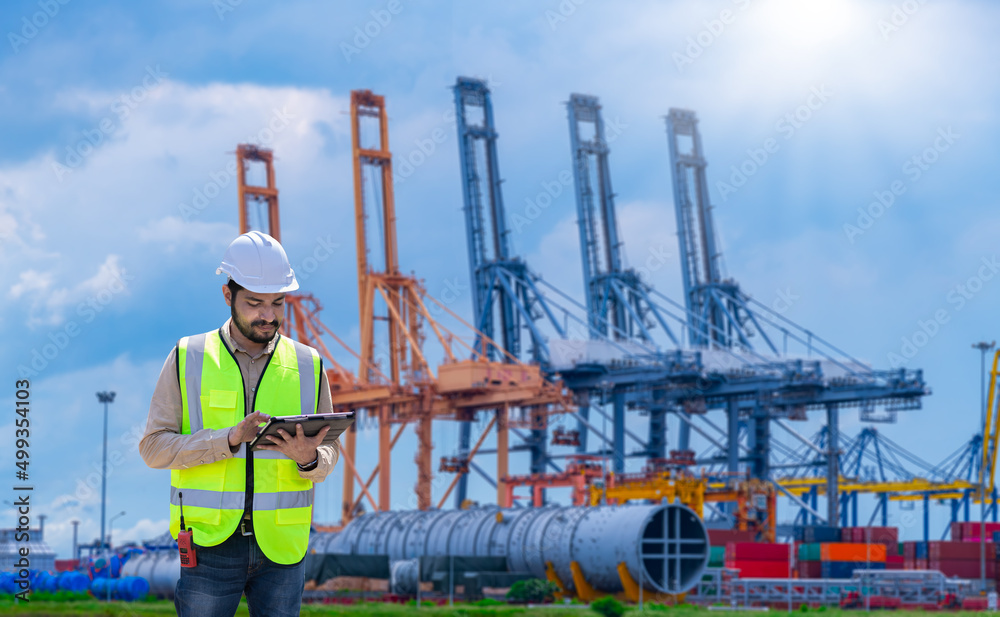 Fototapete Engineer wearing uniform inspection and see detail on tablet with logistics container dock cargo yard with working crane bridge in shipyard with transport logistic import export background.