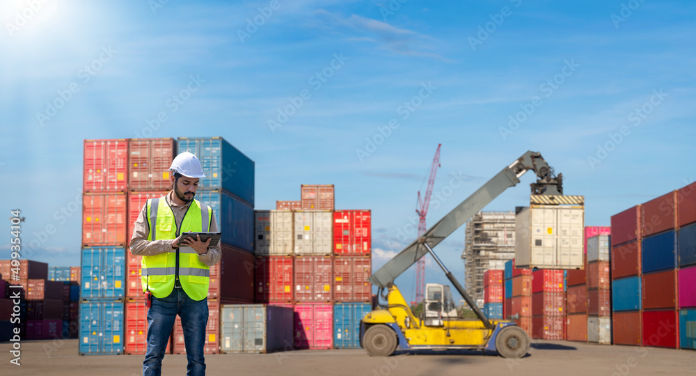 Fototapete Engineer wearing uniform inspection and see detail on tablet with logistics container dock cargo yard with working crane bridge in shipyard with transport logistic import export background.
