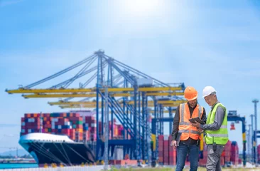 Foto op Canvas Engineer wearing uniform inspection and see detail on tablet with logistics container dock cargo yard with working crane bridge in shipyard with transport logistic import export background. © APchanel