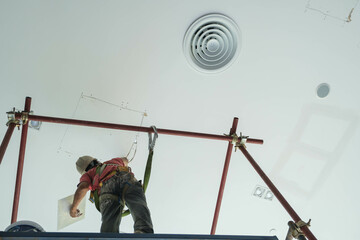 Worker glues mesh to drywall seams in the highlands ceiling wall repair