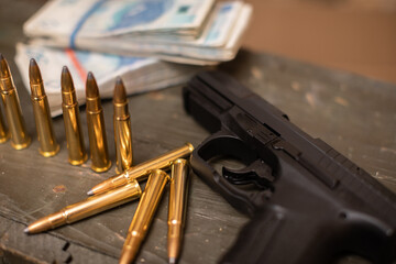 On the crate lie cartridges and a pistol and a bundle of paper bills.