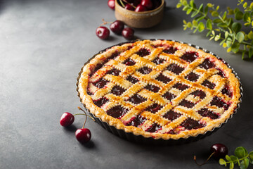 Delicious homemade classic cherry pie with a flaky crust on dark gray background