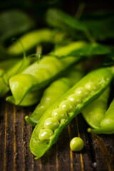 Pods of green peas on a old wooden background close up, soft focus