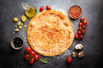 Tasty cheese pizza and cooking ingredients tomatoes and basil on black background. Top view