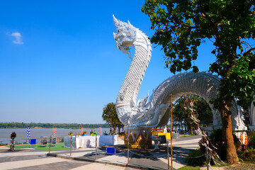 Big White Naga Statue beside Mekong river with blue sky, a tourist attraction at qMukdahan province...