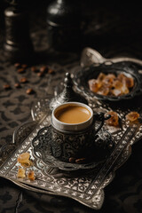 Coffee in metal Turkish traditional cup and coffee beans on dark tile background