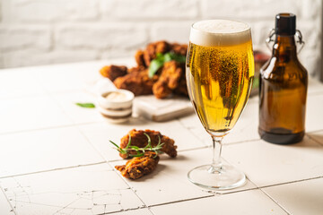 Glass of light beer with chicken wings on white background. Selective focus