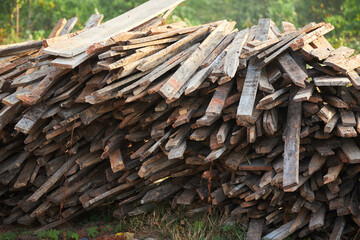 Pile of old wooden planks on green forest background