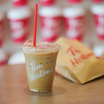 BKK - Apr 11, 2022 : A photo of iced coffee from Tom Hortons cafe. Tim Hortons is a famous coffee shop from Canada. Soft focus and window light.